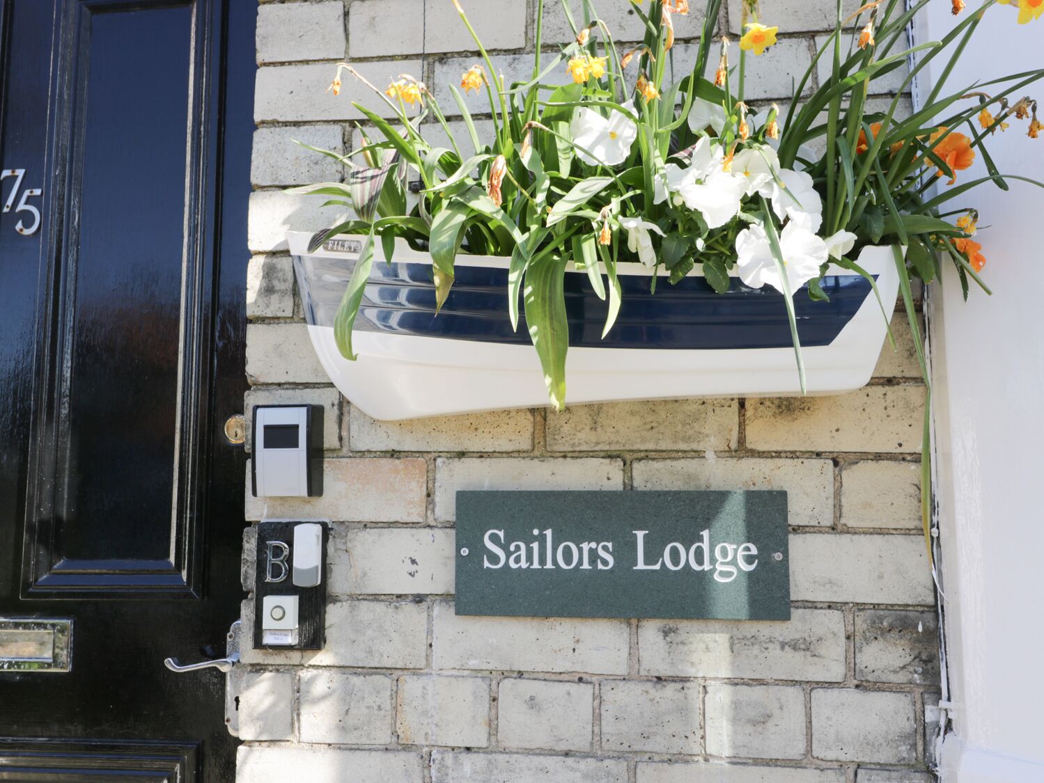 Una puerta negra con un buzón y un cartel que dice "Sailors Lodge".