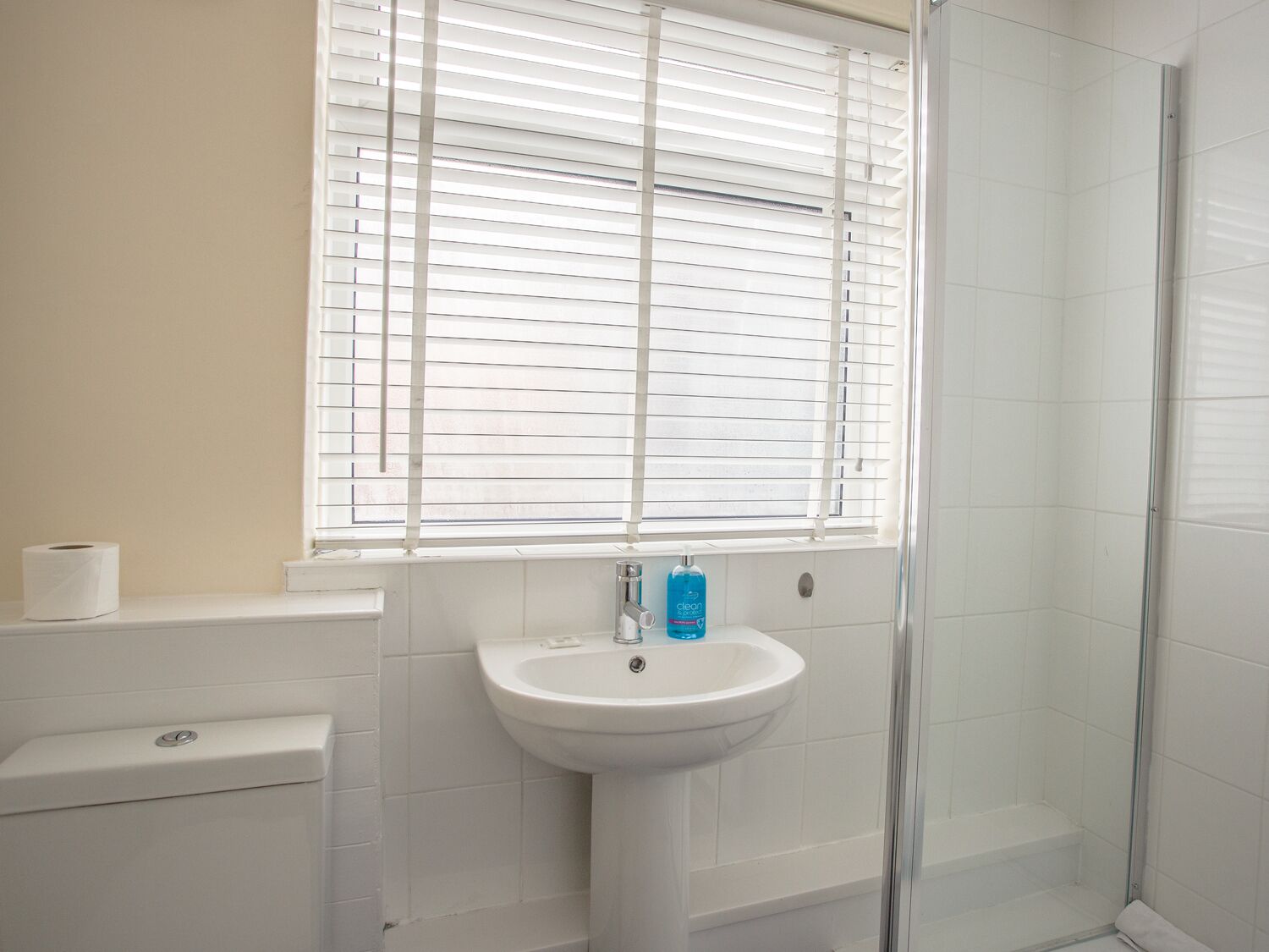 A bathroom with a toilet, a sink, and a glass shower enclosure.