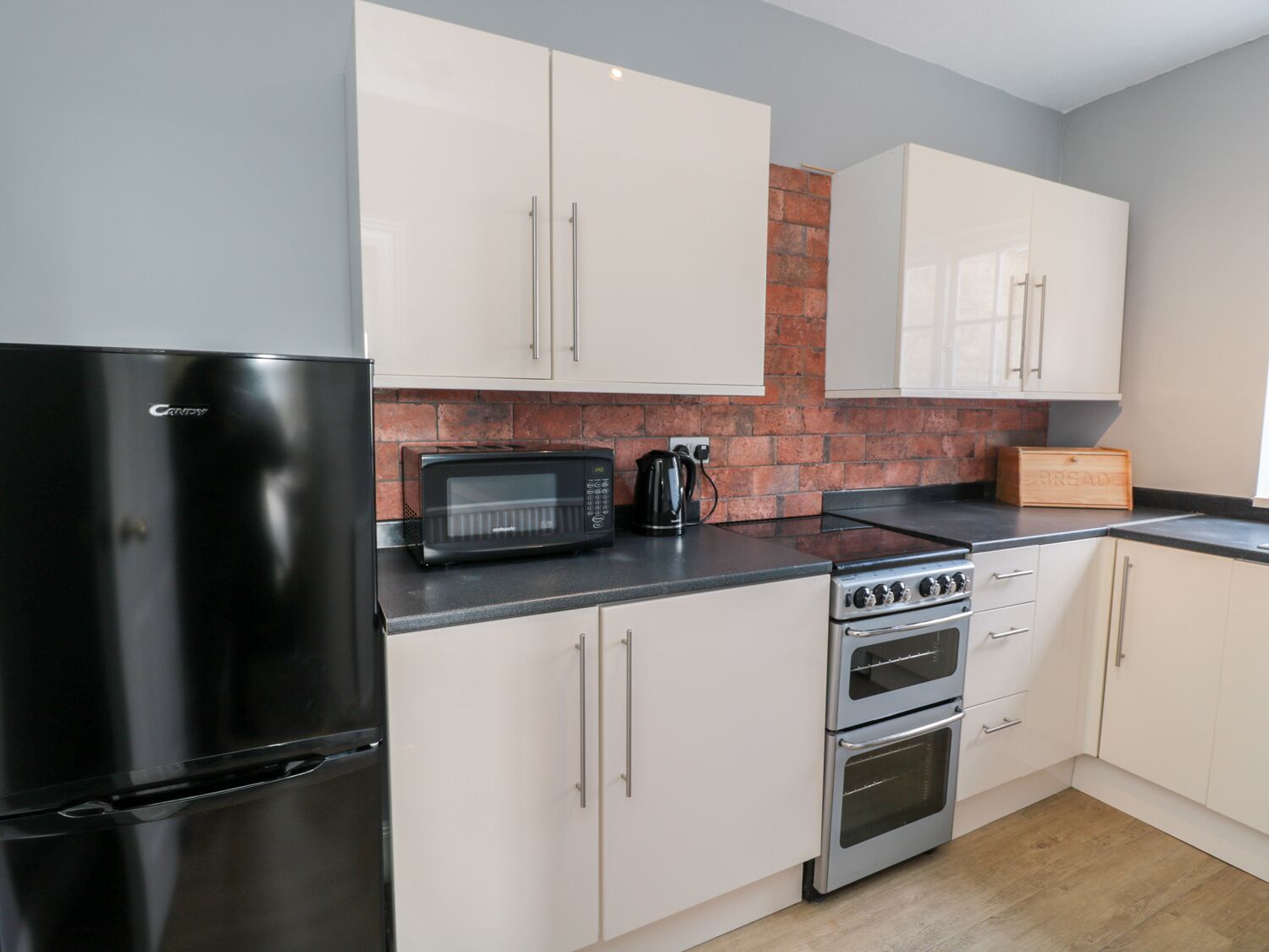 A modern kitchen with a black refrigerator, a microwave, a kettle, and a stove.