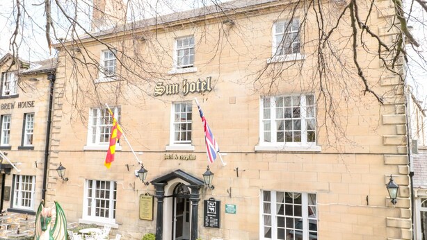 En traditionell byggnad med en skylt på fasaden där det står "Sun Hotel" och "hotell och reception".