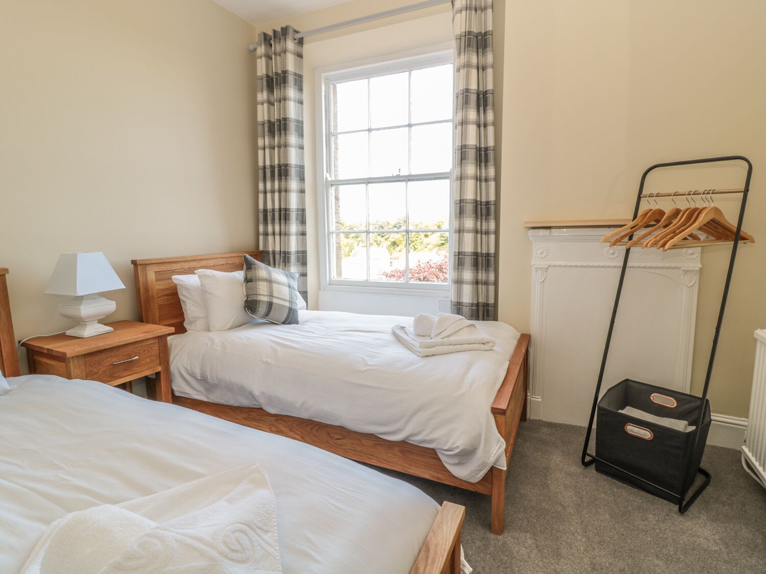 Une chambre d’hôtel avec deux lits, une table de chevet avec une lampe, un radiateur et un porte-vêtements.