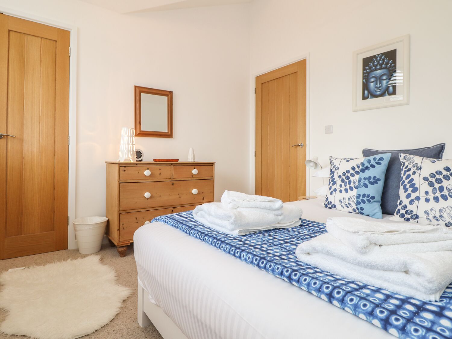 A bedroom with a bed, wooden dresser, and a mirror.