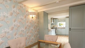 A modern kitchen with light-colored cabinets, a visible stove, and a window with a view of greenery. - Tan Y Goeden (Pwllheli)