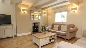 A living room with a television, sofa, fireplace, and wooden flooring. - Tan Y Goeden (Pwllheli)