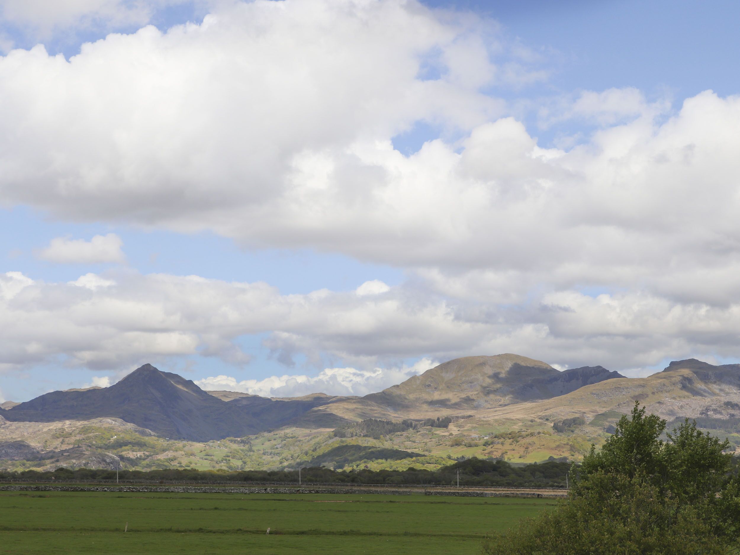 A mountainous landscape with a clear sky and green fields.