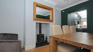 Un comedor con mesa y sillas de madera, chimenea y vistas a una cocina.