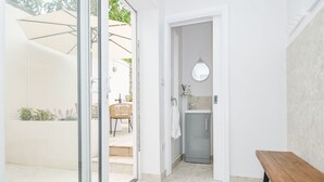 A modern bathroom with a glass shower, a sink with a mirror, and a bench. - Cecily Cottage (Bideford)