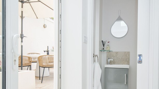 A bathroom with a modern sink, a mirror, and a towel hanging on the wall. - Cecily Cottage (Bideford)