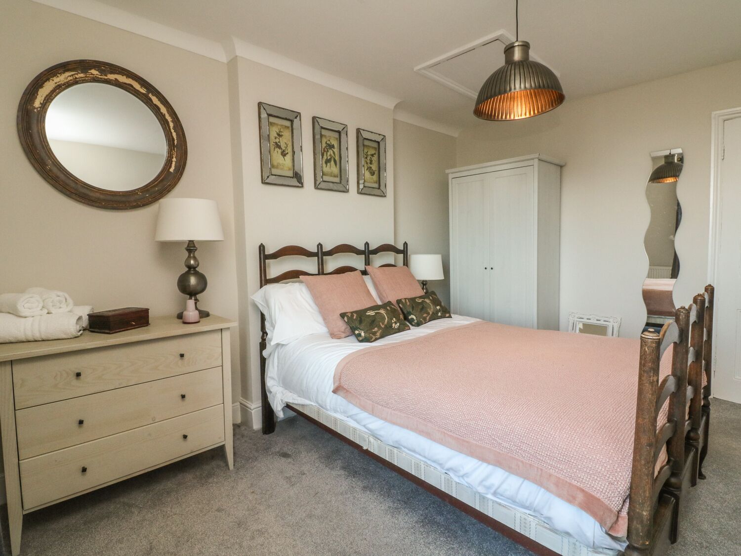 Un dormitorio con cama, cómoda, espejo y armario.
