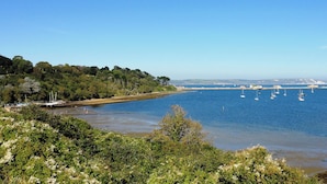 Eine Küstenlandschaft mit freiem Blick auf das Meer, Boote und einen bewaldeten Bereich.