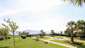 Ein gepflegter Garten mit freiem Blick auf das Meer und die fernen Berge.