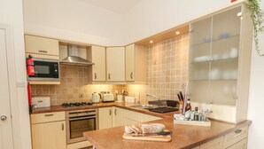 A modern kitchen with a microwave, stove, oven, and a large window with a view. - Apple Tree Cottage (Windermere)