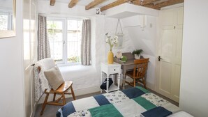 Ein Schlafzimmer mit Bett, Schreibtisch, Stuhl, einem Fenster mit Vorhängen und einer Tür.