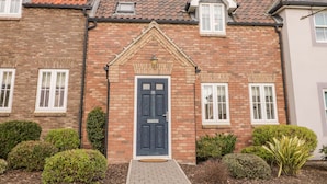A brick house with a dark blue front door, white windows, and a tiled roof. - Bayside Cottage (Filey)