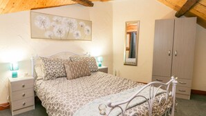 A bedroom with a bed, nightstands, a wardrobe, a mirror, and a dandelion artwork on the wall. - 5 Cliff Lane (Bridlington)