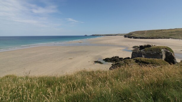 A beach with a clear sky, a sandy shore, and grassy dunes. - The Beach Halt (Perranporth)