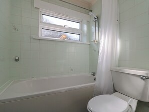 Un baño con bañera, inodoro y ventana.