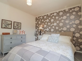 Ein Schlafzimmer mit Bett, Schminktisch und blumigem Wandpapier.
