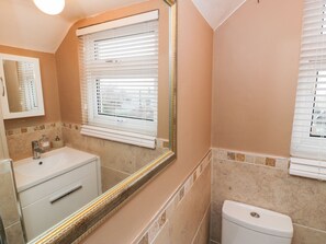A bathroom with a white sink, a mirror, and a toilet.