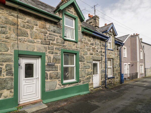 A stone building with green trim and a white door.
