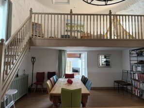 A spacious dining area with a high ceiling, a staircase, and a view of the outside. - The Oast House (Weymouth)