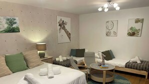 Una habitación de hotel con una cama, un sofá, una silla, una mesita y obras de arte en las paredes.