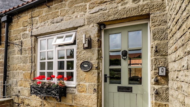 A stone cottage with a green door, a window with a flower box, and a sign reading "Raygill Cottage". - Raygill Cottage (Whitby)