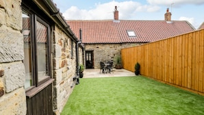 A stone house with a tiled roof, a wooden fence, and a well-maintained lawn. - Raygill Cottage (Whitby)