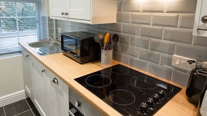 Una cocina moderna con una placa de inducción negra, un tostador y un organizador de utensilios.