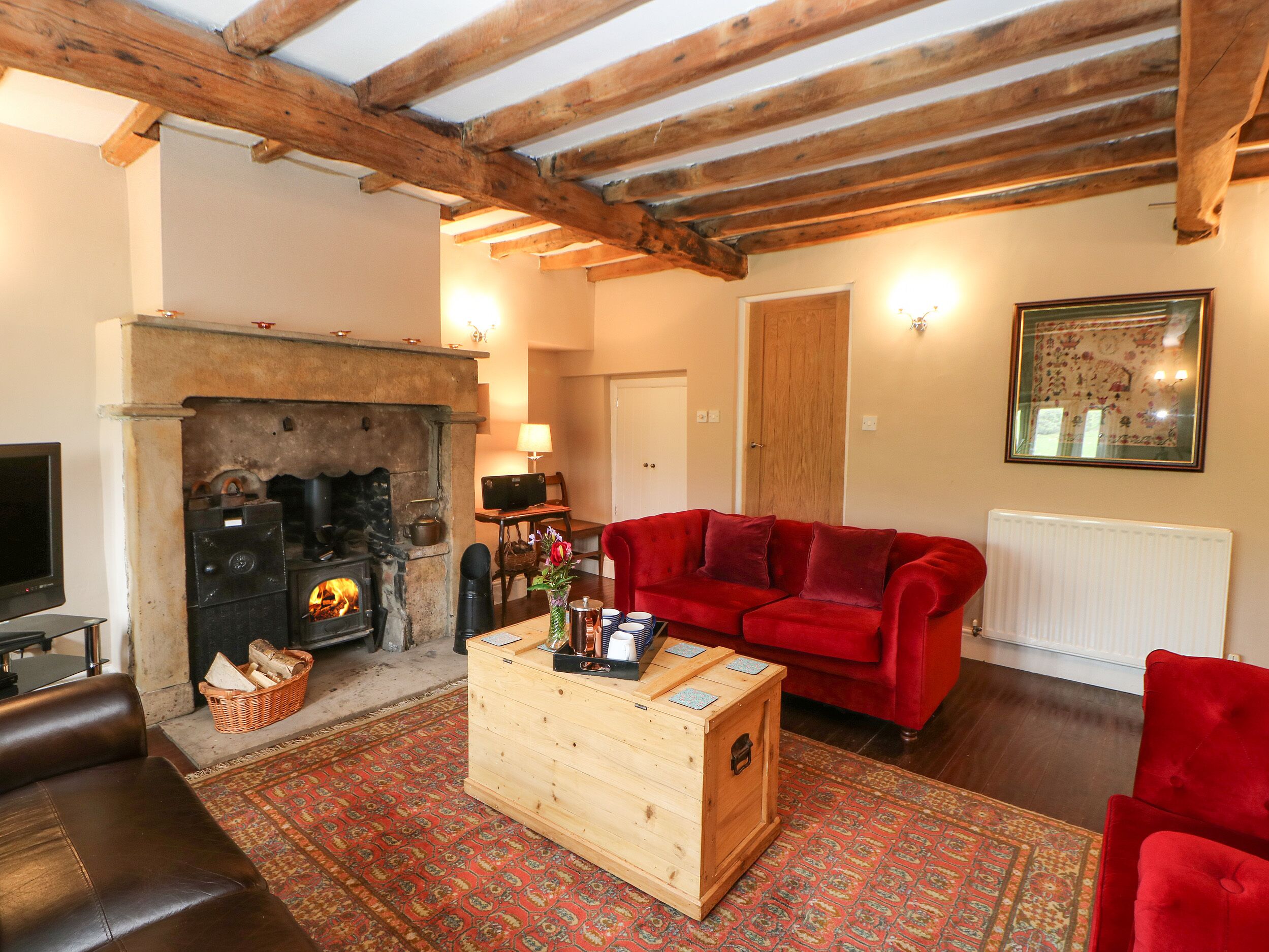 A cozy living room with a fireplace, a red sofa, and a wooden coffee table.