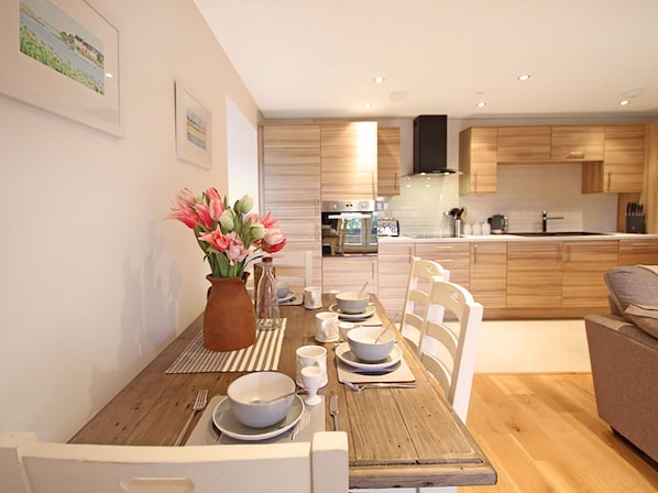 Enjoy meals in this stylish kitchen and dining area, featuring an oven, stainless steel range hood, and seating for four.