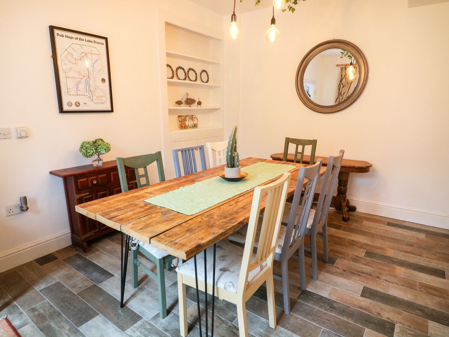 Une salle à manger avec une table en bois, des chaises, une carte accrochée au mur, des étagères et un miroir.