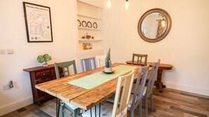 A dining room with a wooden table, chairs, a map on the wall, shelves, and a mirror. - Giddy Goose (Windermere)