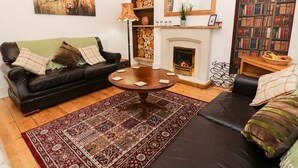 A cozy living room with a fireplace, a black leather sofa, a coffee table, and a bookshelf filled with books. - Giddy Goose (Windermere)
