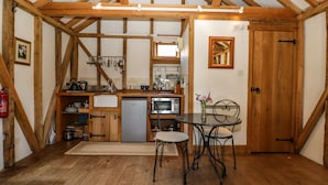 Eine rustikale Küche mit Holzbalken, einem Spülbecken, einem Kühlschrank und einem Essbereich mit Metallstühlen.