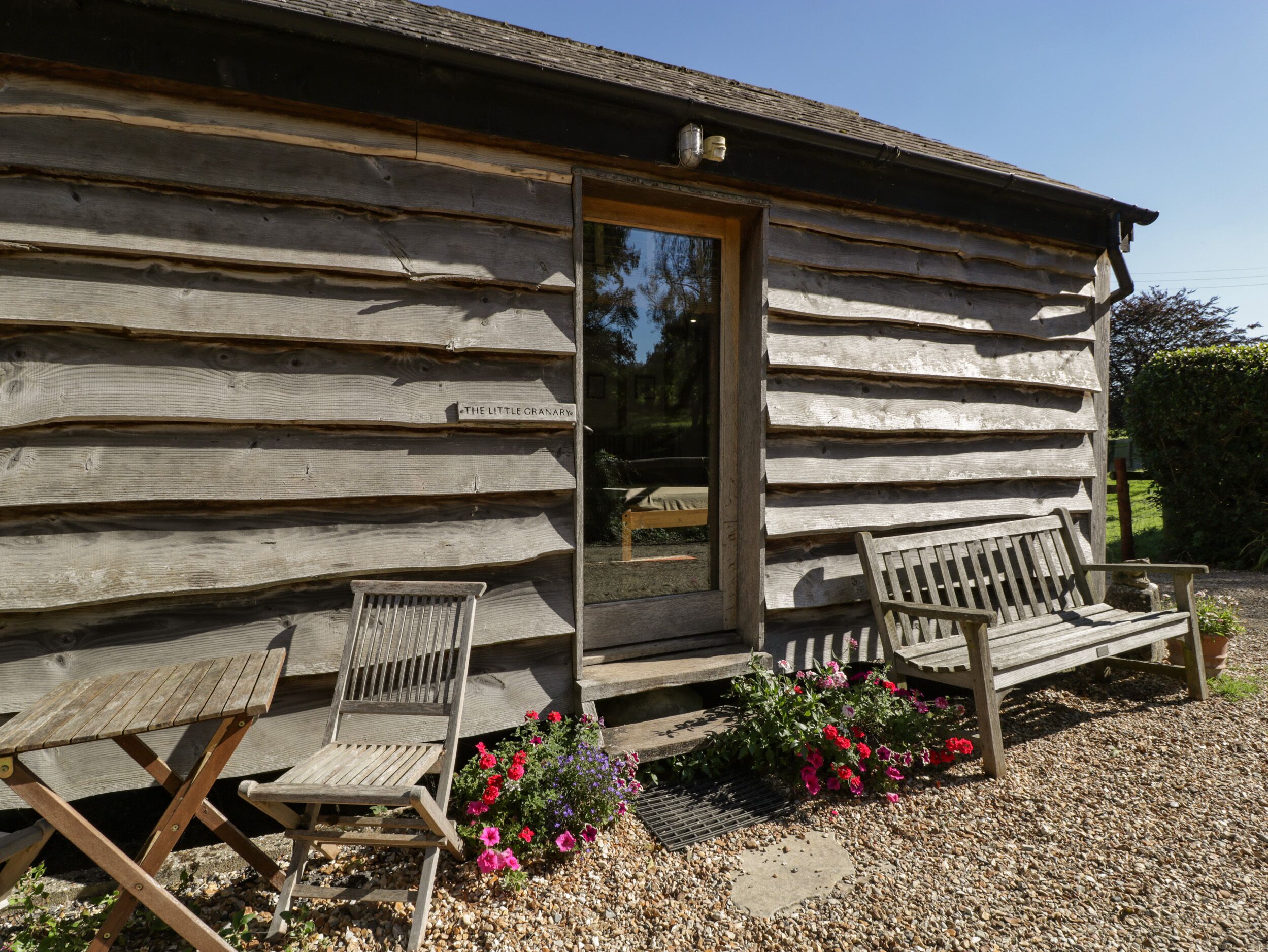 A rustic wooden cabin with a door, two wooden benches, and a small table.