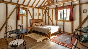 Ein gemütliches Schlafzimmer mit Holzbalkendecke, einem Bett, einem kleinen Tisch und einem Stuhl.