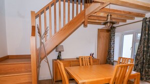 A wooden staircase leading to a dining area with a table and chairs. - Crooked Hill Cottage (Ammanford)