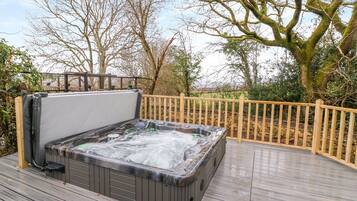Relax in a hot tub on a raised deck with a scenic view.