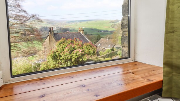 A window with a view of a rural landscape, including houses and greenery. - Silver Hill Cottage (Harrogate)