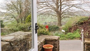 A stone wall with a window, a red mailbox, and a view of a tree and landscape. - Silver Hill Cottage (Harrogate)