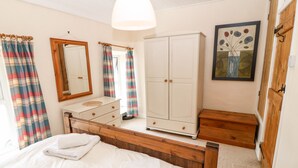 Quarto com cama, penteadeira e guarda-roupa, com cortinas xadrez e espelho.