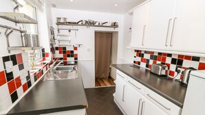 Uma cozinha compacta com armários brancos, bancada preta e backsplash com azulejos vermelhos, pretos e brancos.