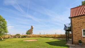 Une pelouse bien entretenue, agrémentée d’un bunker de sable, de vestiges en pierre et d’un bâtiment en briques doté d’un balcon.