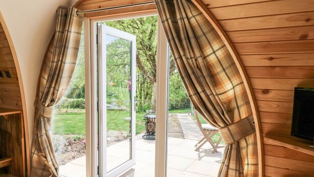 A room with a large sliding glass door leading to an outdoor patio. - Chapel Pod (Saltash)