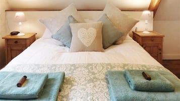 A neatly made bed with a patterned bedspread, multiple pillows, and two bedside tables with lamps.