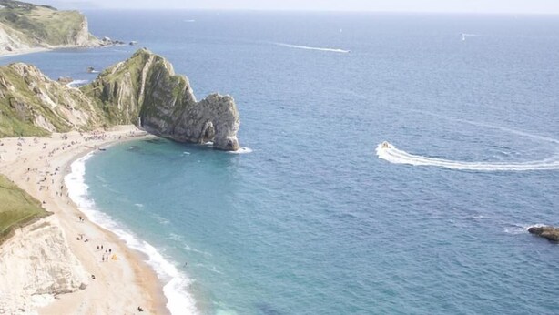 A coastal beach with a prominent rock formation, clear blue waters, and a sandy shoreline. - Warmwell Lodge (Dorchester)