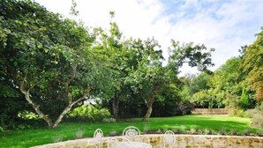 A stone patio with a round table and four chairs, surrounded by lush greenery and trees. - Warmwell Lodge (Dorchester)