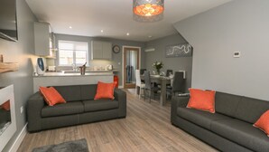 Una sala de estar moderna con dos sofás grises, un tapete gris y una zona de comedor con mesa y sillas.