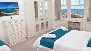 A bedroom with a bed, a desk, a wardrobe, and a view of the sea. - Weymouth Bay Apartment B (Weymouth)